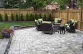 a patio with chairs and a table in the middle of it