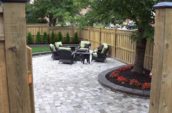 a patio with chairs, a table and a tree