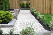 a garden with a brick walkway and a wooden fence